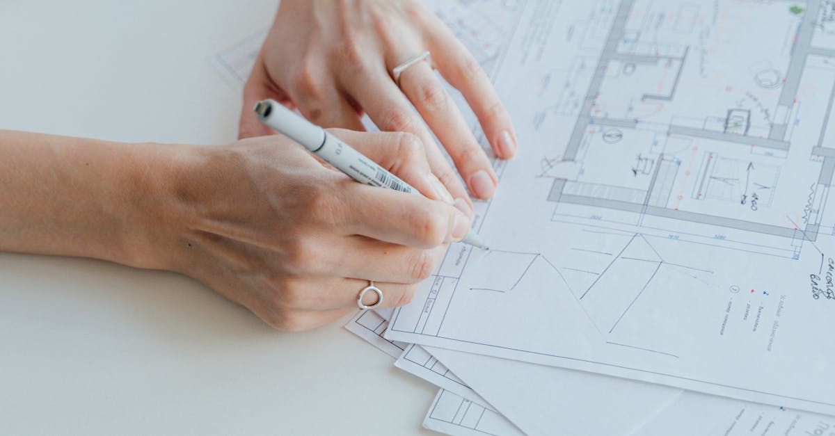 An architect writes notes on design plans while sitting at a desk, focusing on details.