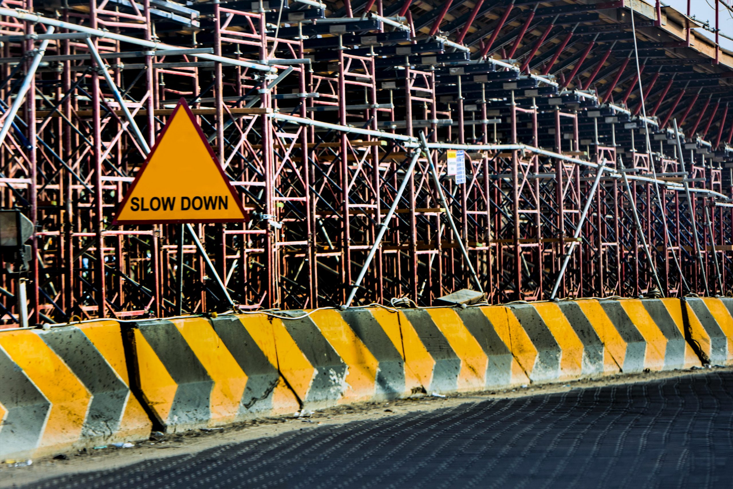 Construction site with a 'Slow Down' sign amid scaffolding in Kuwait.