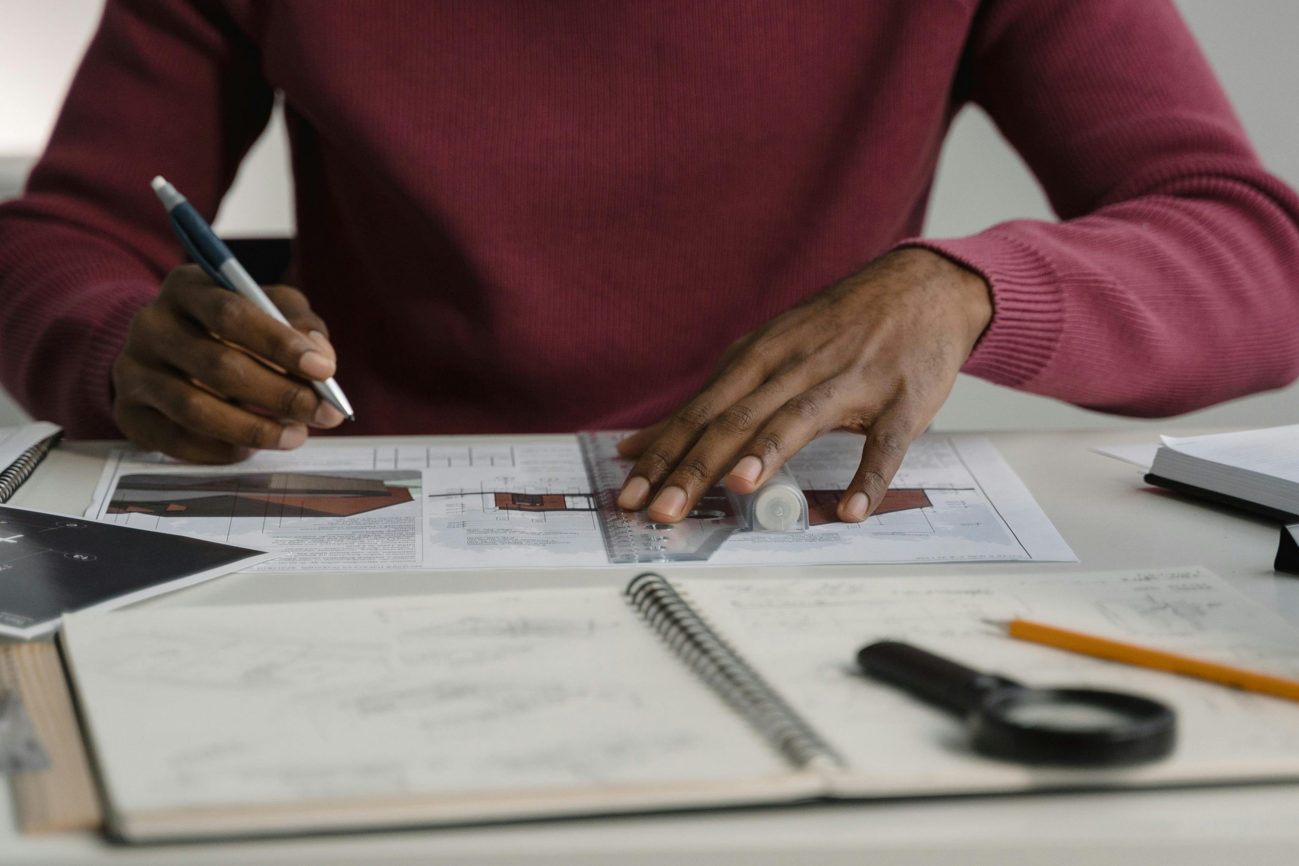 Professional architect working with blueprints and tools at a desk.